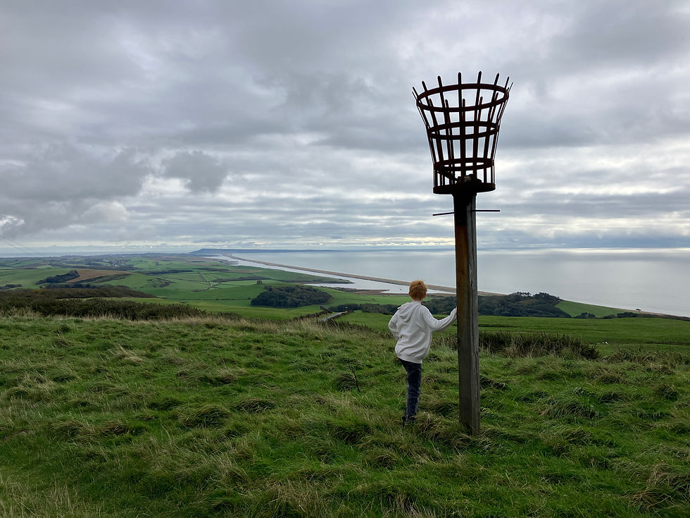 Boy admiring the view of Chesil Beach and Portland Bill from Abbotsbury Hill Fort