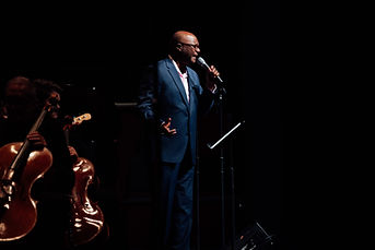 Man singing into microphone on stage.