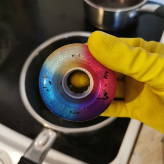 A rubber gloved hand is holding the wheel with two colours applied. The pan of dye bath is in the background.