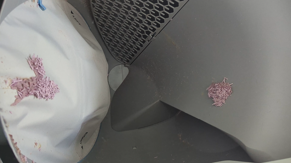 Close-up of a white and gray machine with pink pellets spilled on its surface; LEFT and RIGHT labels are visible.