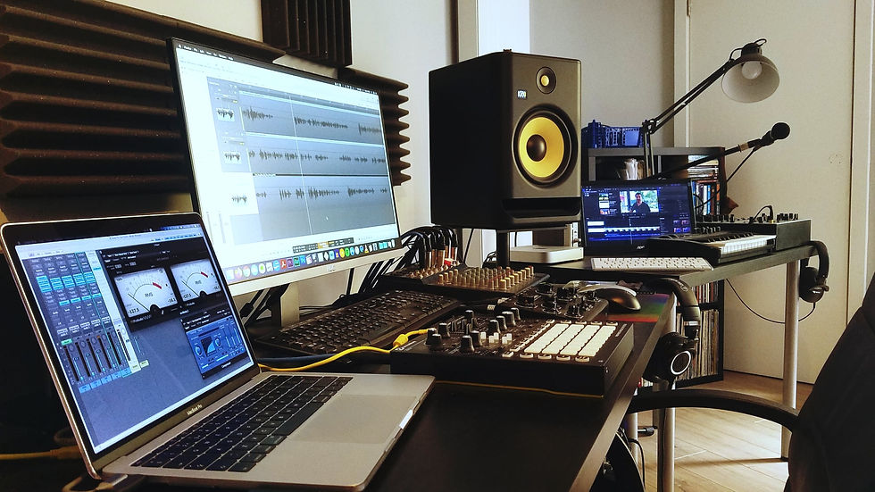 Professional audio and video studio setup with mixing console, monitor speakers, multiple computer and screens displaying audio and video software