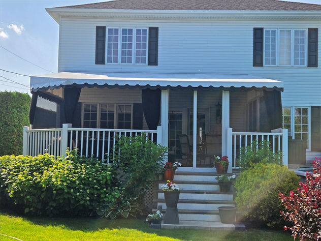 White house with awning and stairs. Auvent stationnaire permanent. Auvents Signature.