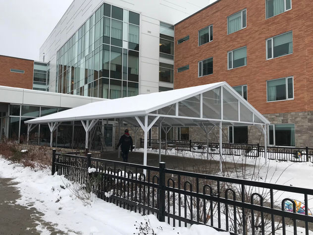 Person walks under a frosted awning at a building entrance. Auvents Signature.