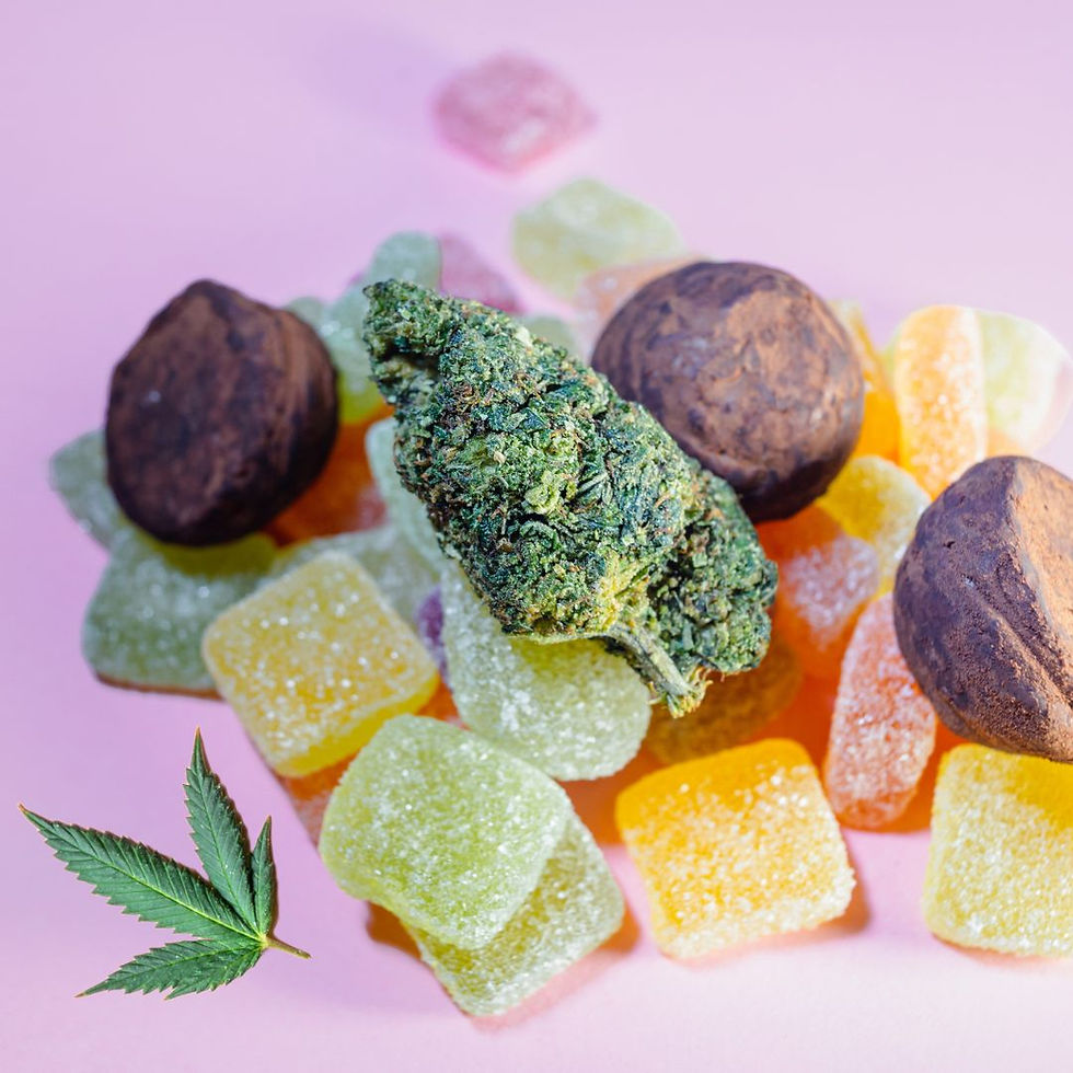 a pile of coloured gummies and brownies with a cannabis nug on top and cannabis leaves