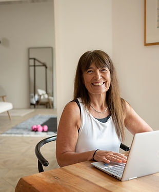 Picture of Sharon Clapp in a white top smiling in front of a computer