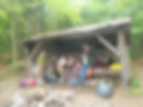 a group of campers wake up in a lean-to structure