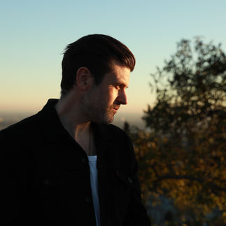 Side profile of a man standing outside looking downward,