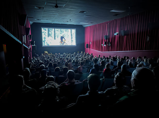 Inside The Vic theatre in Victoria, the audience is watching a motorcycle film on the big screen.