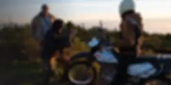 A director and camerman shooting a scene with a motorcycle overlooking a forested area.