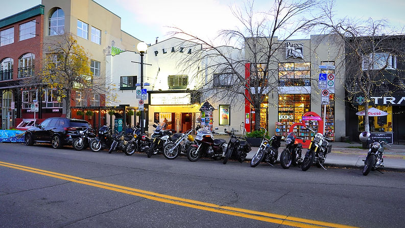 A row of motorcycles parked outside of a movie theatre