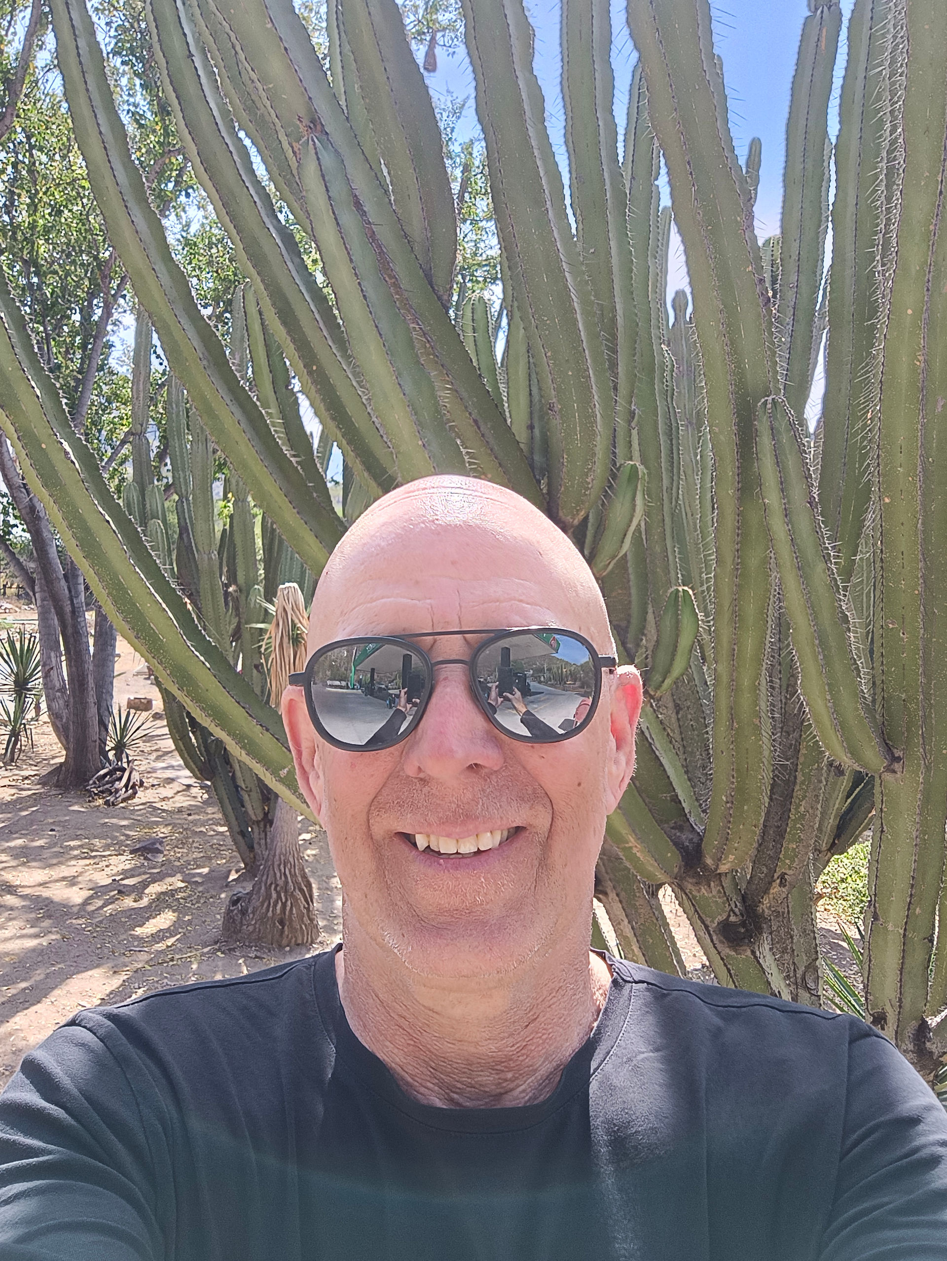 A man smiling in front of a large cactus