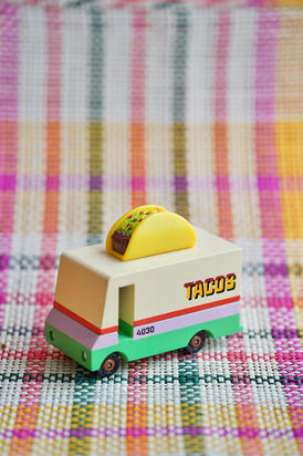 Set design Jouet en bois design Candylab Toys représentant un camion à tacos, mis en scène sur un fond graphique multicolore