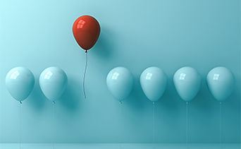 One red balloon rising among blue balloons, representing standing out in competitive Assistant Psychologist applications.