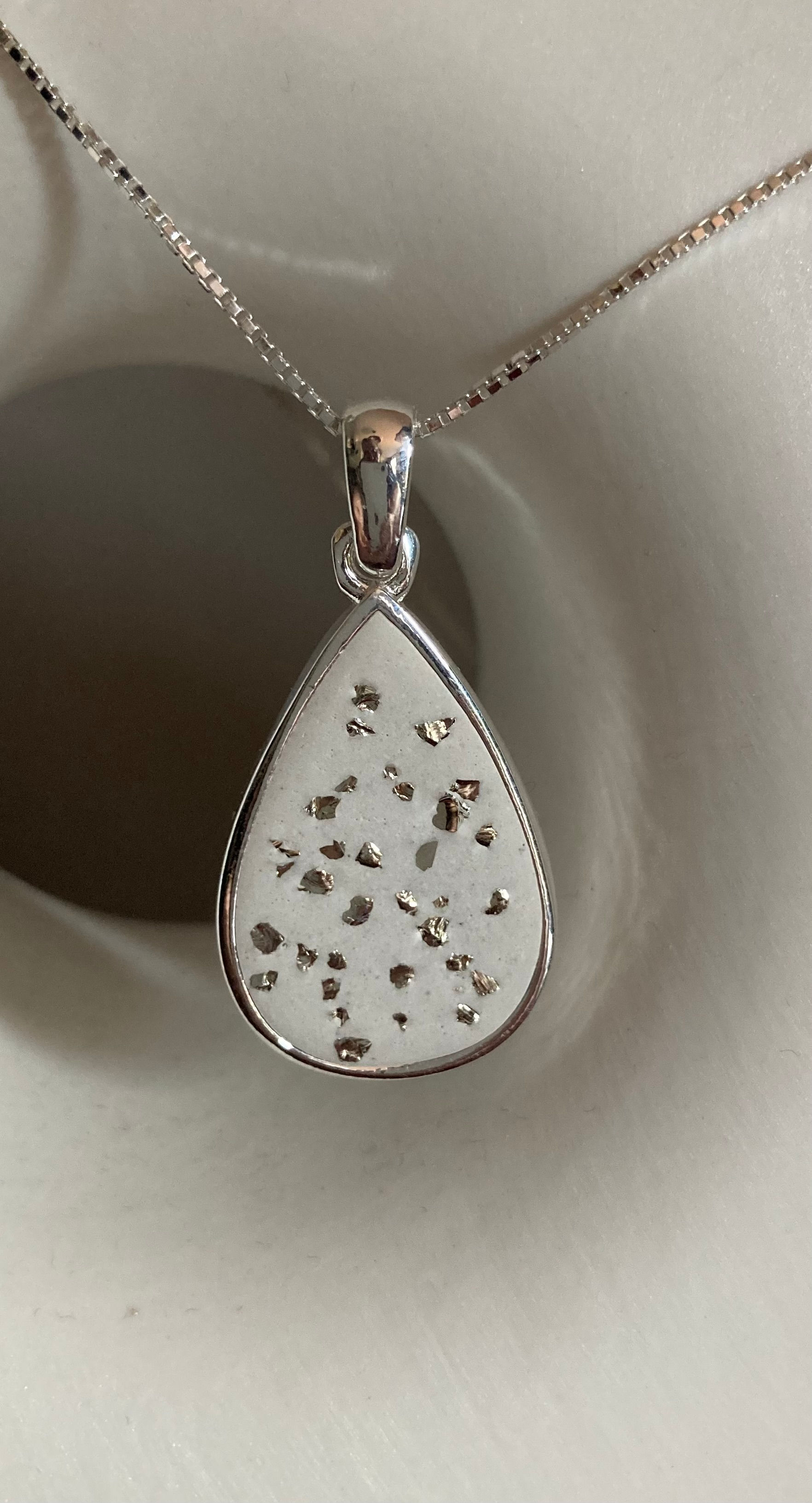 Pendentif en argent en forme de goutte travaillé au béton blanc avec incrustations de paillettes de verre argentées et sa cha