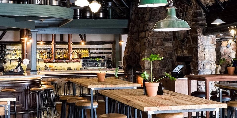 Restaurant interior with stone walls and wooden tables – A cozy bar and dining space with exposed stone walls, wooden tables