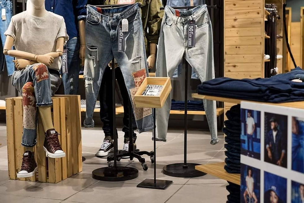 Two pairs of Levi’s 501 jeans in light and distressed denim on standalone displays, surrounded by mannequins and folded denim