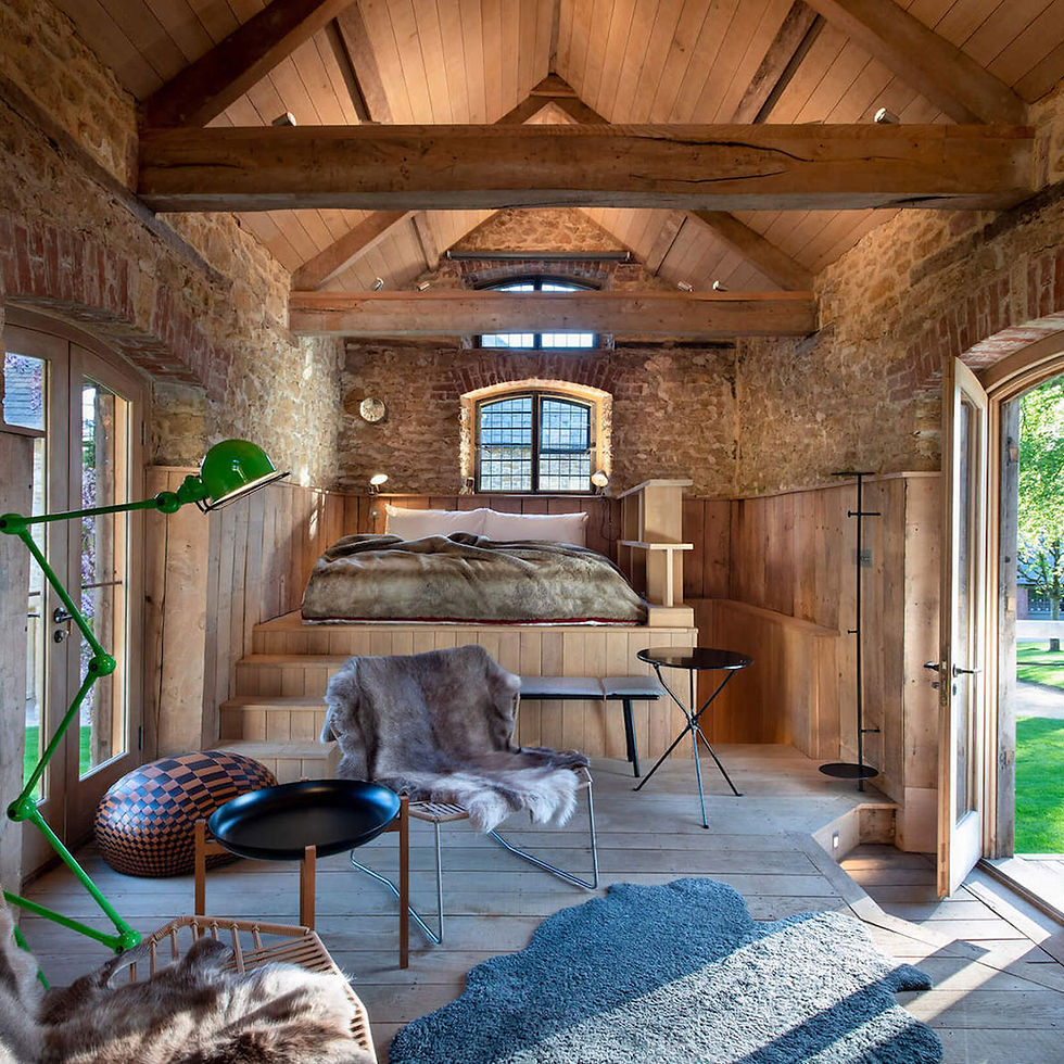 A large spacious barn hotel room with luxurious furniture and a large bed.