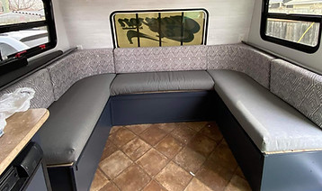 The inside of a camper with custom grey bench cushions.