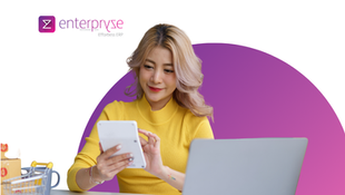 Distributor calculating product costs on a calculator and laptop beside a stack of cartons — landed cost calculation ERP reveals the true cost of goods