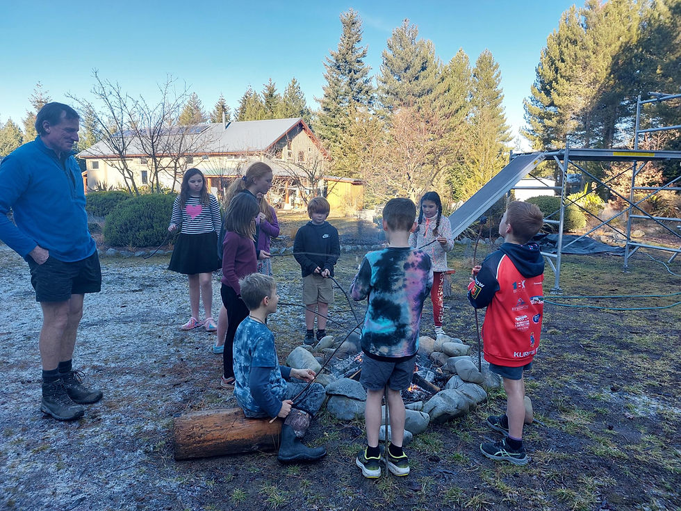 Children roasting marshmallows around a backyard fire after a birthday party obstacle course, illustrating how shared experiences matter more than perfection.