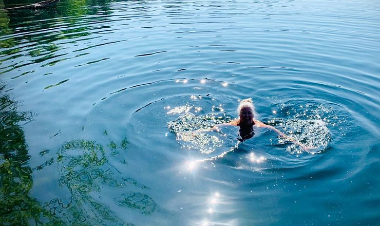 A woman with grey hair swimming in a resort pool