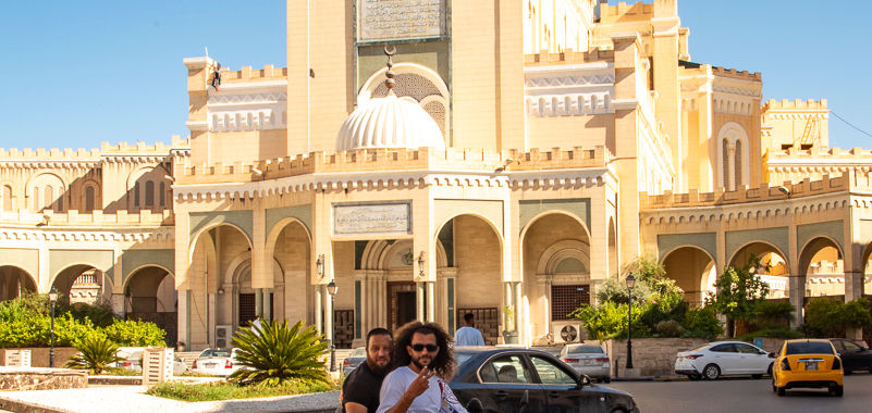 A motorcyclist and passenger pose for a photo in the traffic circle in front of Masjid Maidan Al-Jazair Square in Tripoli, Libya.