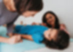 Girl receiving acupuncture from acupuncturist while Mom looks at her sweetly in background
