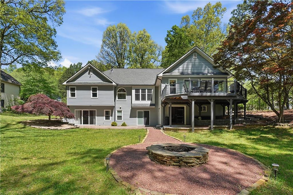 Rear exterior of traditional home with elevated deck, patio, and landscaped backyard with fire pit
