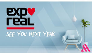 Eine Grafik zur EXPO REAL. An einer hellblauen Wand steht in Schwarz das Logo der EXPO REAL mit einem roten Herzen und darunter der Schriftzug „SEE YOU NEXT YEAR“. Rechts daneben sind ein moderner Sessel, eine Pflanze und das Logo der APARTMENTHELDEN zu sehen.