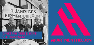 Die drei Geschäftsführer der APARTMENTHELDEN GmbH feiern lächelnd ihr 1-jähriges Firmenjubiläum mit Torte und Sekt vor einem Banner. Rechts im Bild das Firmenlogo in Pink auf blauem Grund.