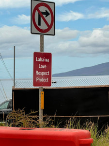 Sign on side of road overlooking ocean reads Lahaina Love Respect Protect