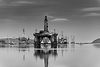 Black and white offshore oil rigs in calm water.