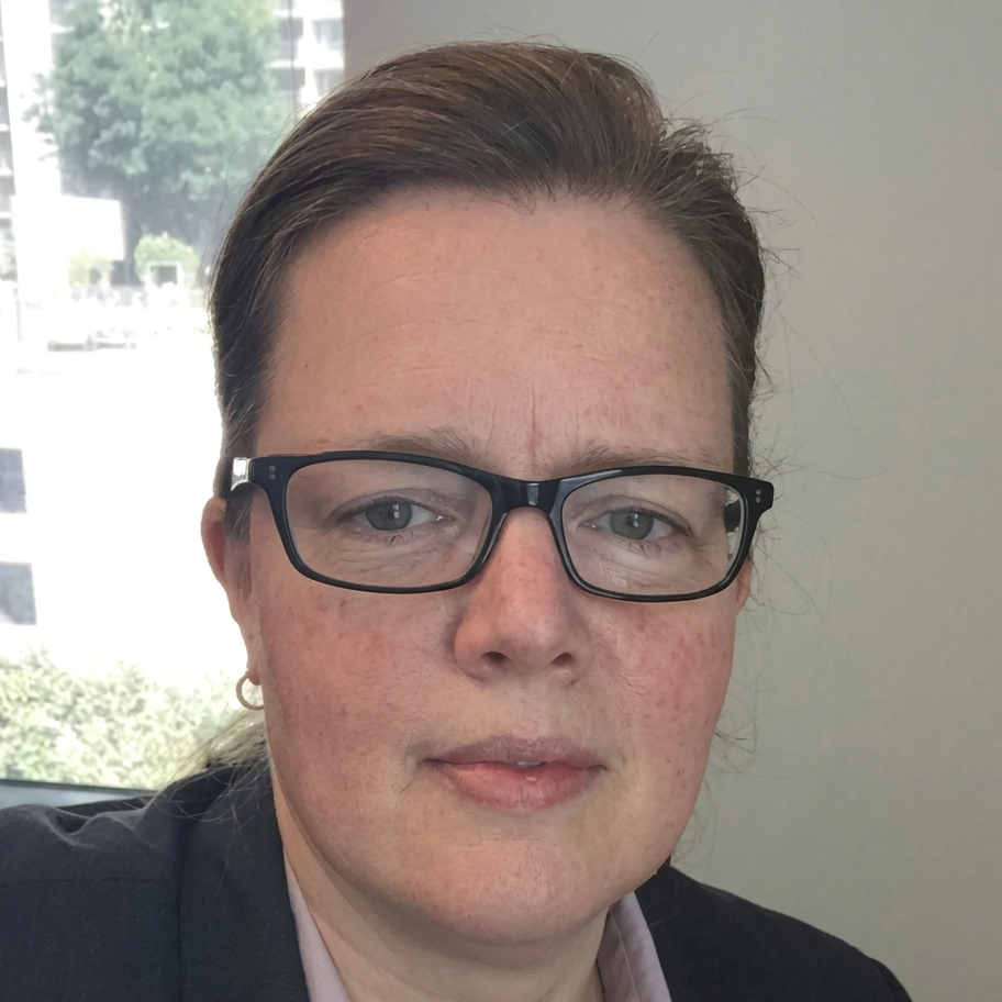 Portrait photography of a woman wearing glasses. She is looking directly at the camera in a professional setting.