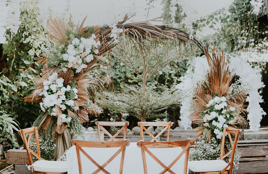 パンパースや白い花で装飾されたアーチを背景にした6人掛けのテーブル、美しくコーディネートされたウェディング装飾