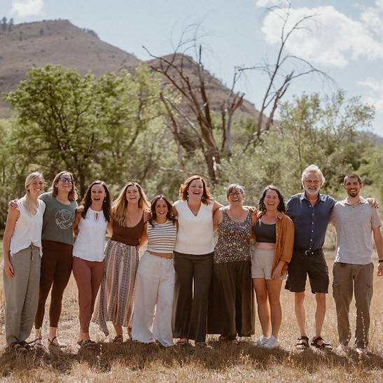 Dori Lewis and Dr. Shannon Hughes are flanked by 8 students in front of trees and mountains.