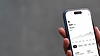 iPhone 16 mockup in a woman's hand with concrete backdrop (Mockuuups Studio) (2).png