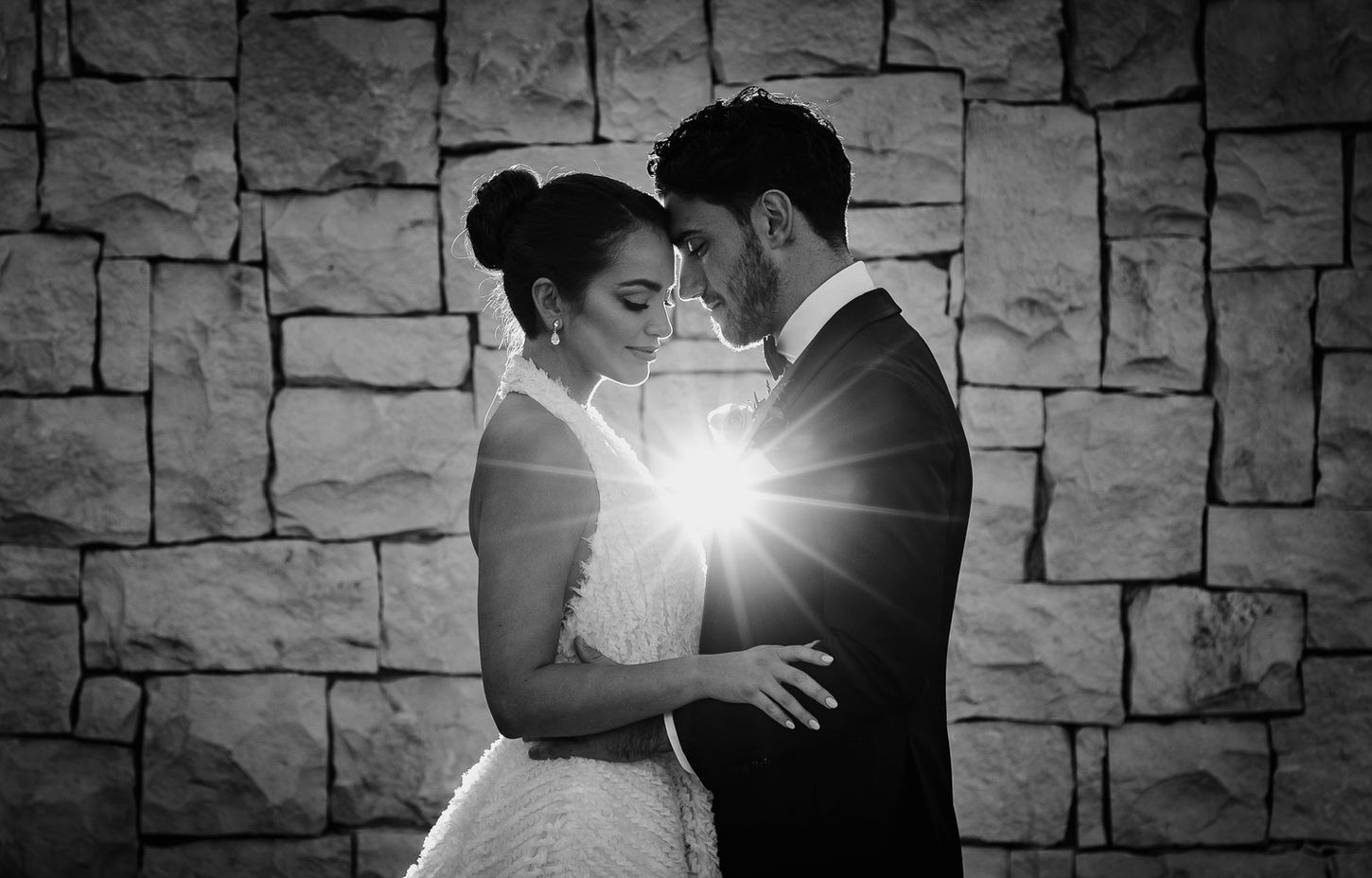 The Bride and Groom pose in front of a textured wall on location at the Iconic InterContinental Sydney Double Bay, in black and white.