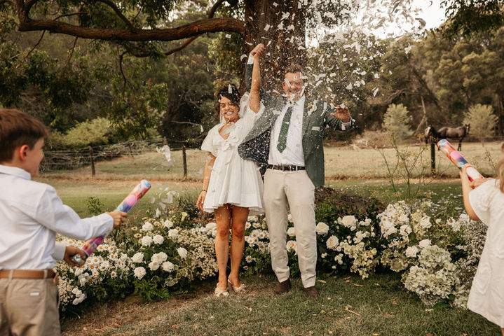 Bride and groom celebrating with confetti in a Sydney garden wedding ceremony