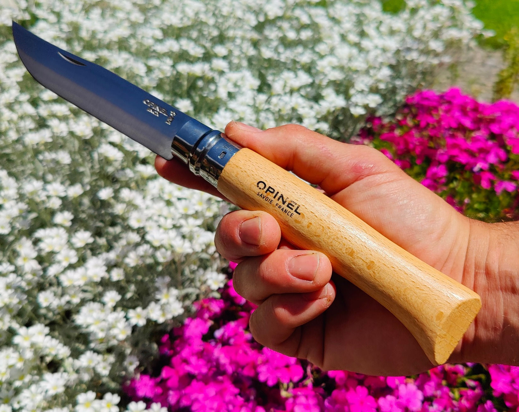 Opinel n°12 lame inox manche hêtre dans la main fond fleurs