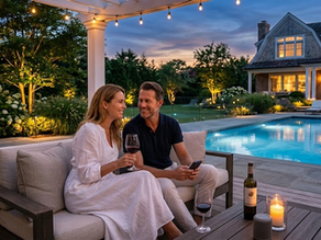 A man and woman drinking wine on a patio by the pool.
