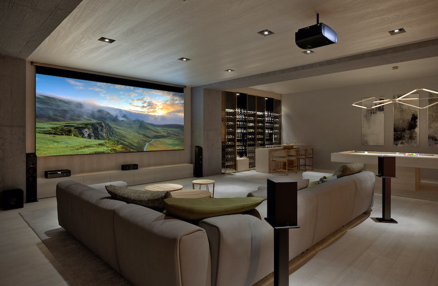 Home theater with brown sectional couch, projector and colorful mountain scene displaying on large screen.