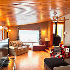 Salon confortable avec foyer, télévision et vue lac