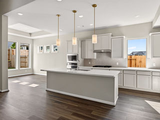 Modern kitchen with white island and pendant lighting.