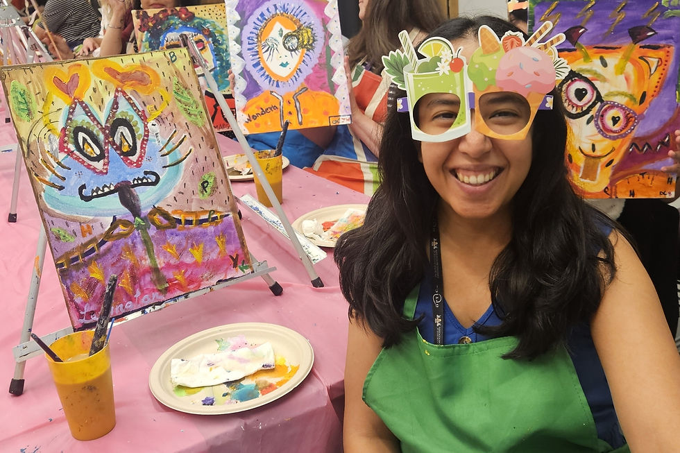 Team taking part in a creative painting workshop, smiling and holding colourful artwork