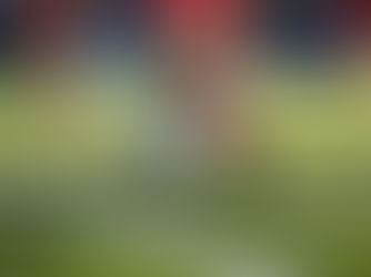 Piłkarz w czerwonych getrach uderza piłkę podczas meczu na murawie - intensywny wysiłek fizyczny generujący stres oksydacyjny w mięśniach nóg