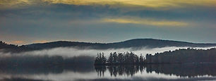 Fog forms over Kezar Lake New Hampshire. Photograph by Ken Schuster.
