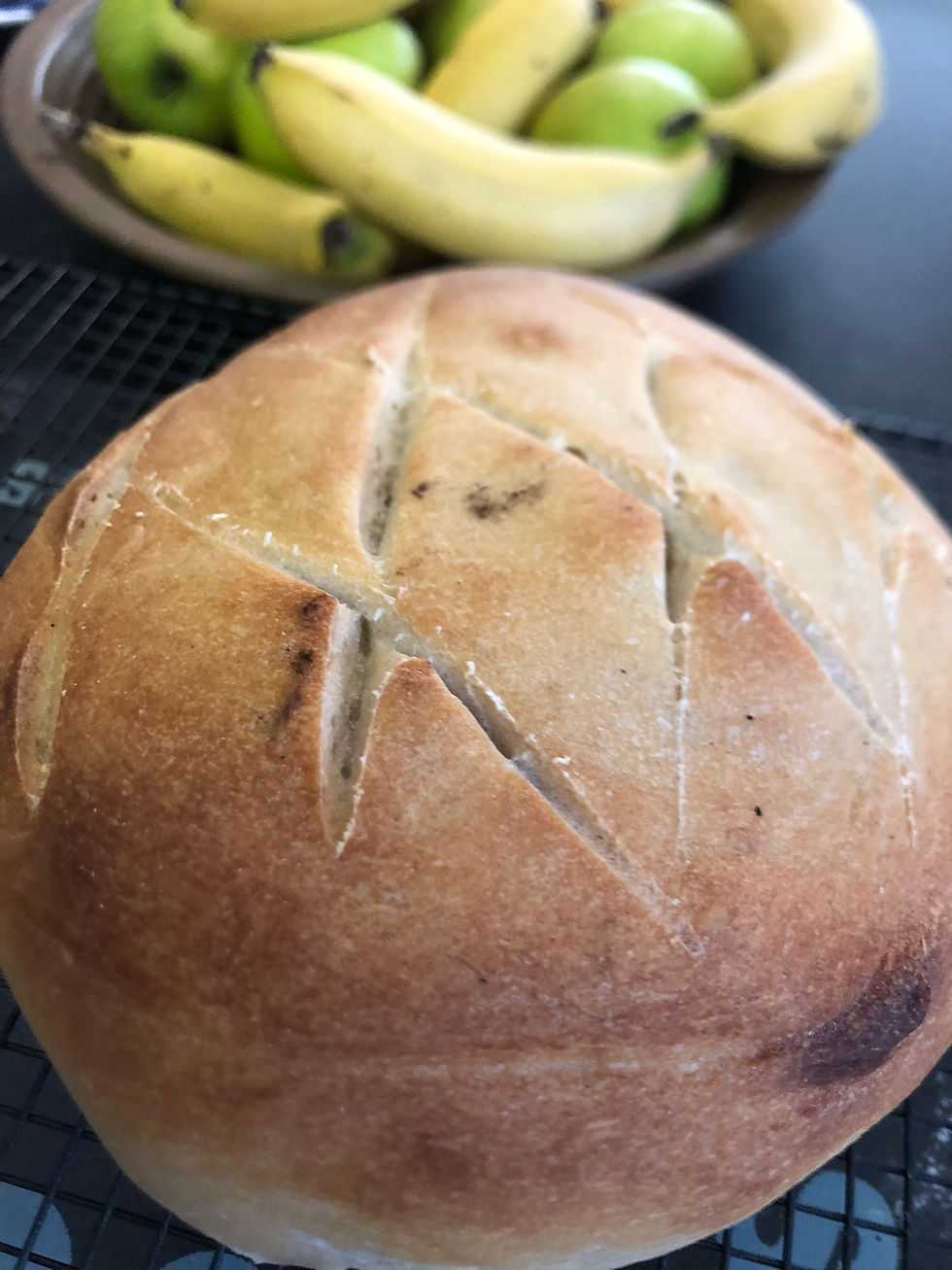 A round loaf of bread and fruitbowl in the background