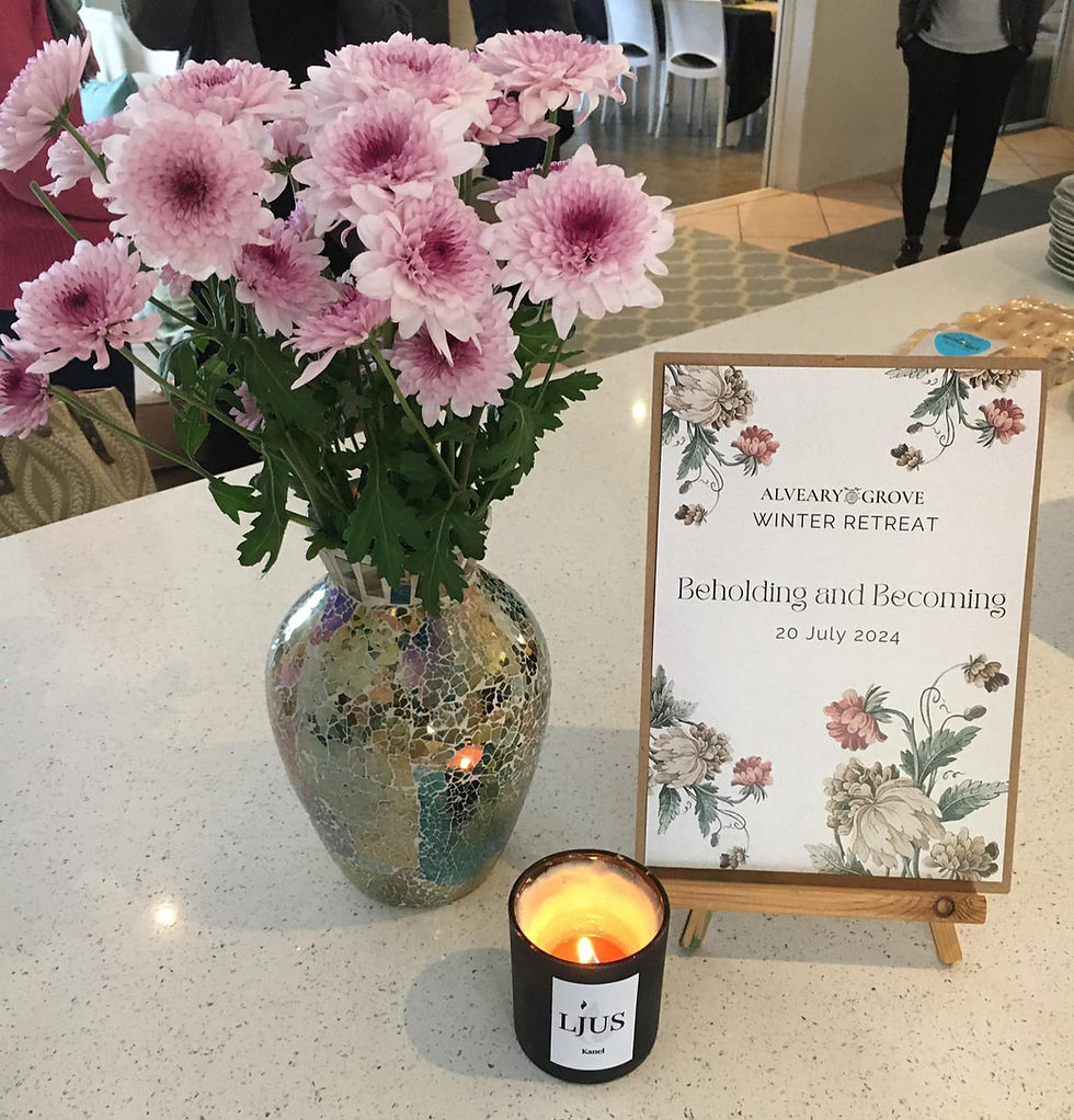 A vase with pink flowers, a candle, a welcome note.