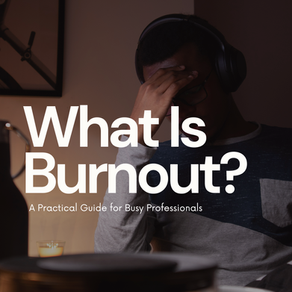 Person with headphones holding head, appearing stressed. Text: "What Is Burnout? A Practical Guide for Busy Professionals." Dimly lit room. Burnout at work