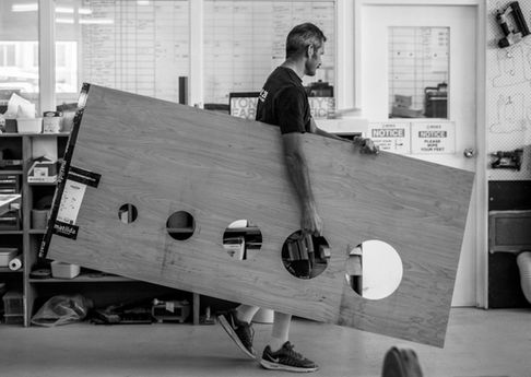 Man carrying large, cut-out wood panel, small business photography